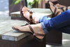 Feet relaxing in Shamma All Browns sandals on bench