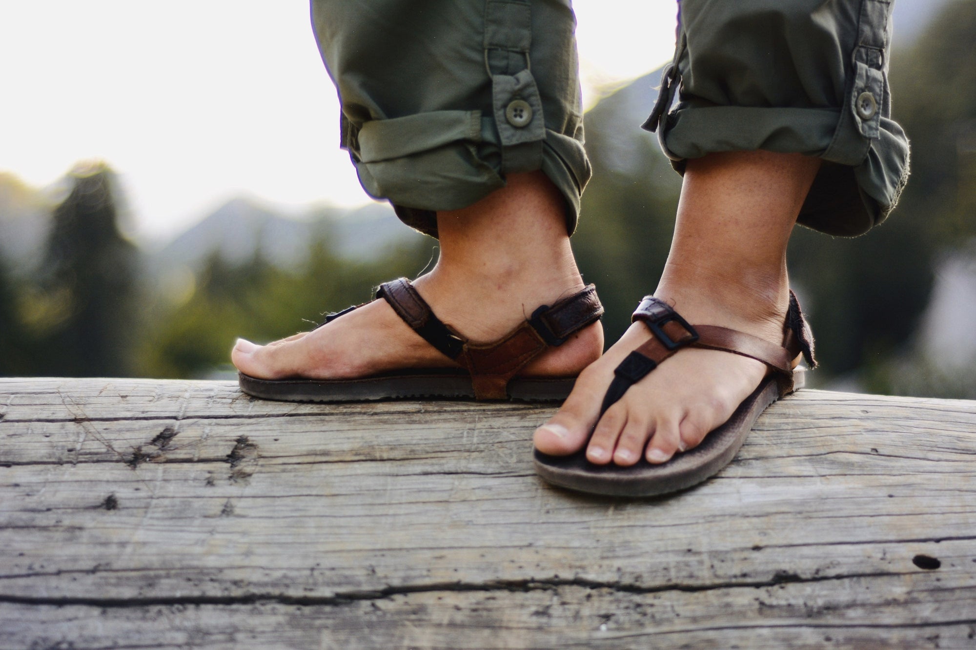 A man standing on a log outdoors wearing Super Goats.