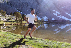 A runner wearing Shamma Warriors while running near a mountainside.